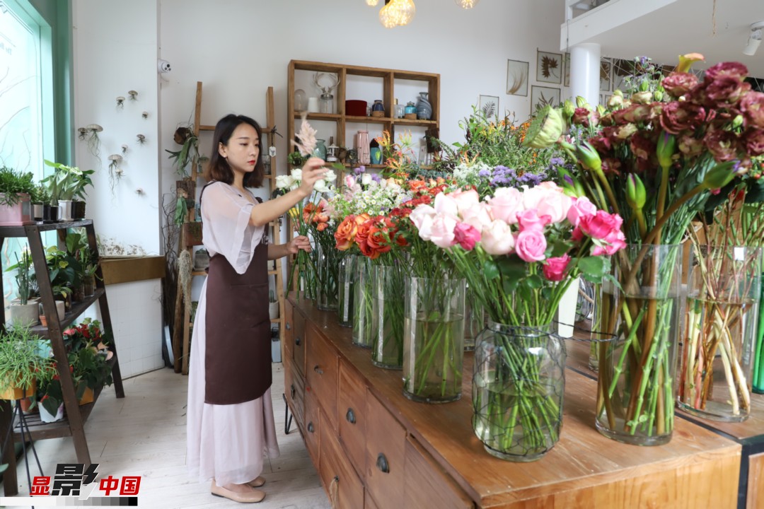 王黎媛是一名河南姑娘，在昆明念完大學(xué)后，就再也舍不下春城的藍(lán)天陽光、青山碧水，更舍不下這里的四時(shí)繁花，于是就干脆留了下來，成了一名媒體人。2017年的時(shí)候又毅然辭去工作，創(chuàng)業(yè)開起了花店，成了都市里的一名“花房姑娘”。圖為王黎媛在自己的花店中整理鮮花。新華網(wǎng) 周亞平/攝 念新洪/文